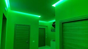 A hallway with green lighting, wooden doors, and a marble floor. - B&B CADIFRA PORTAPICCOLA (Naples)