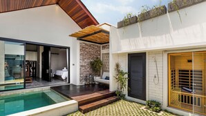 Una casa moderna con piscina, un patio con terraza de madera y un pequeño jardín.