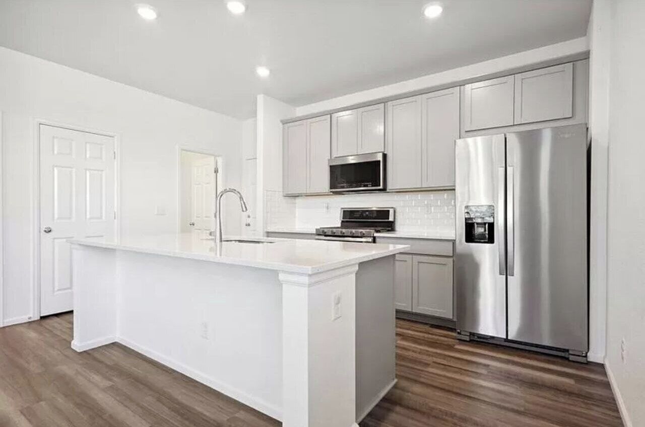 A modern kitchen with white cabinetry, stainless steel appliances, and a central island.