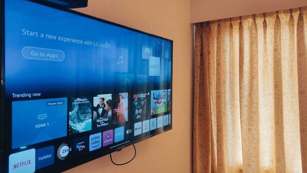 A flat-screen TV mounted on a wall displaying a streaming interface with various app icons and a "Trending now" section. - Nachiappa Palaniappa Grand Inn (Kodaikanal)