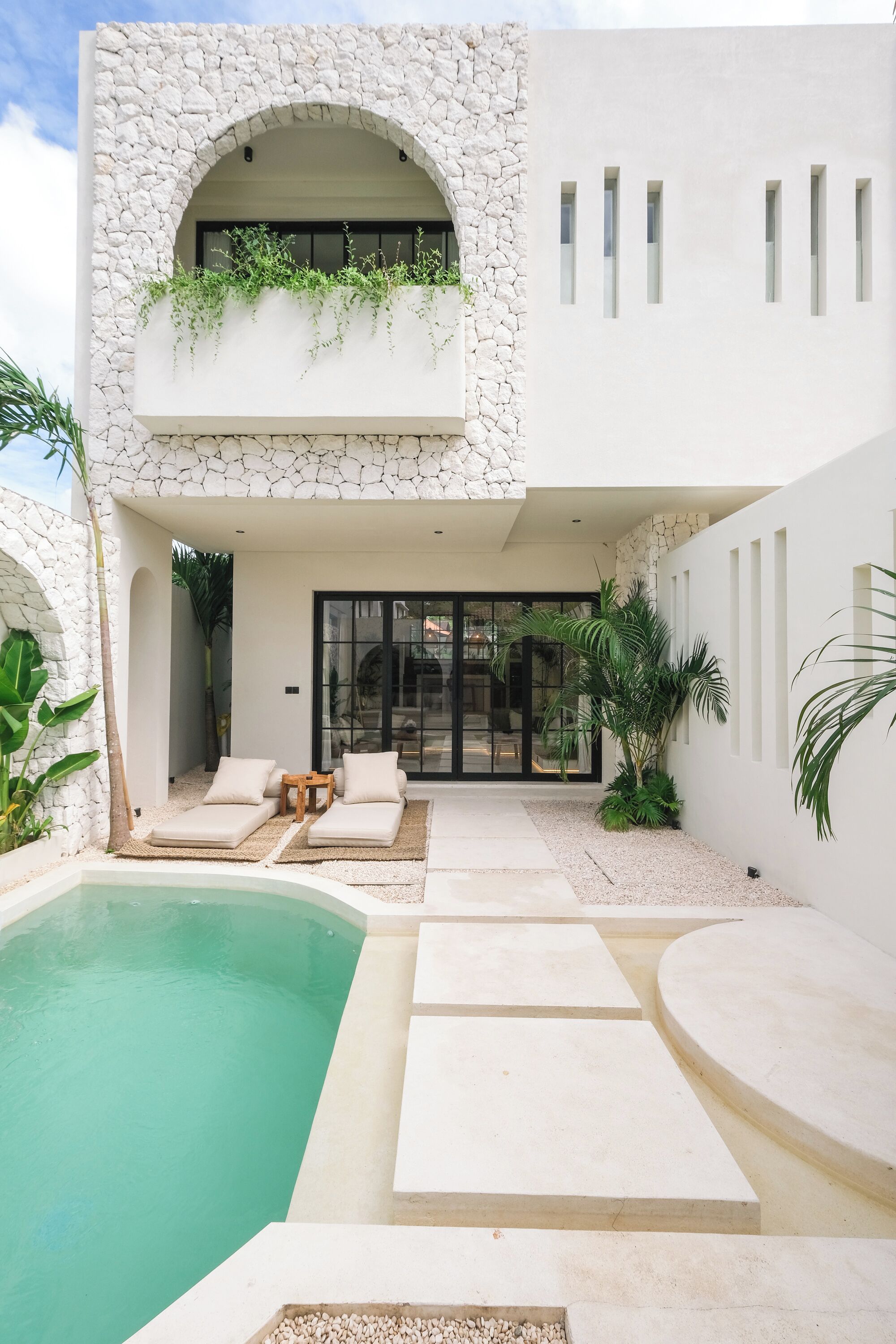 A modern building with a stone facade, a pool, and outdoor seating.