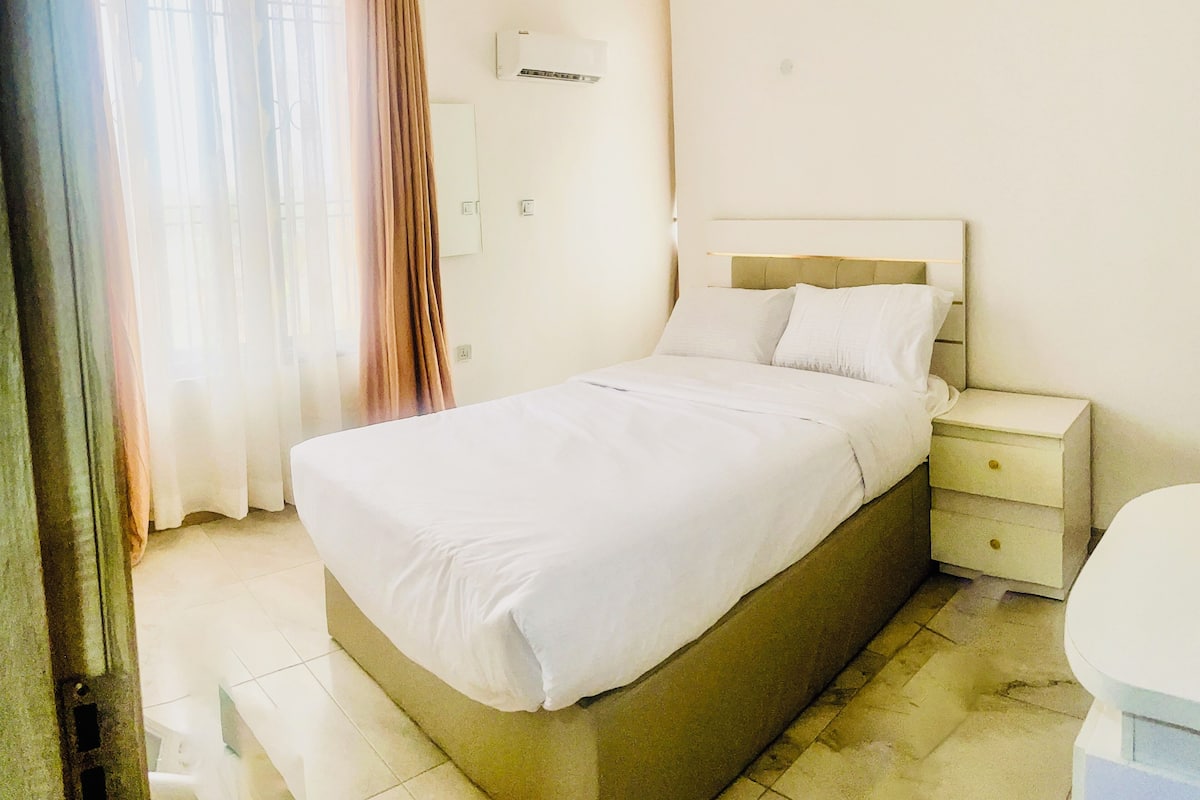 Une chambre d’hôtel comprenant un lit, une table de chevet et une petite salle de bain.