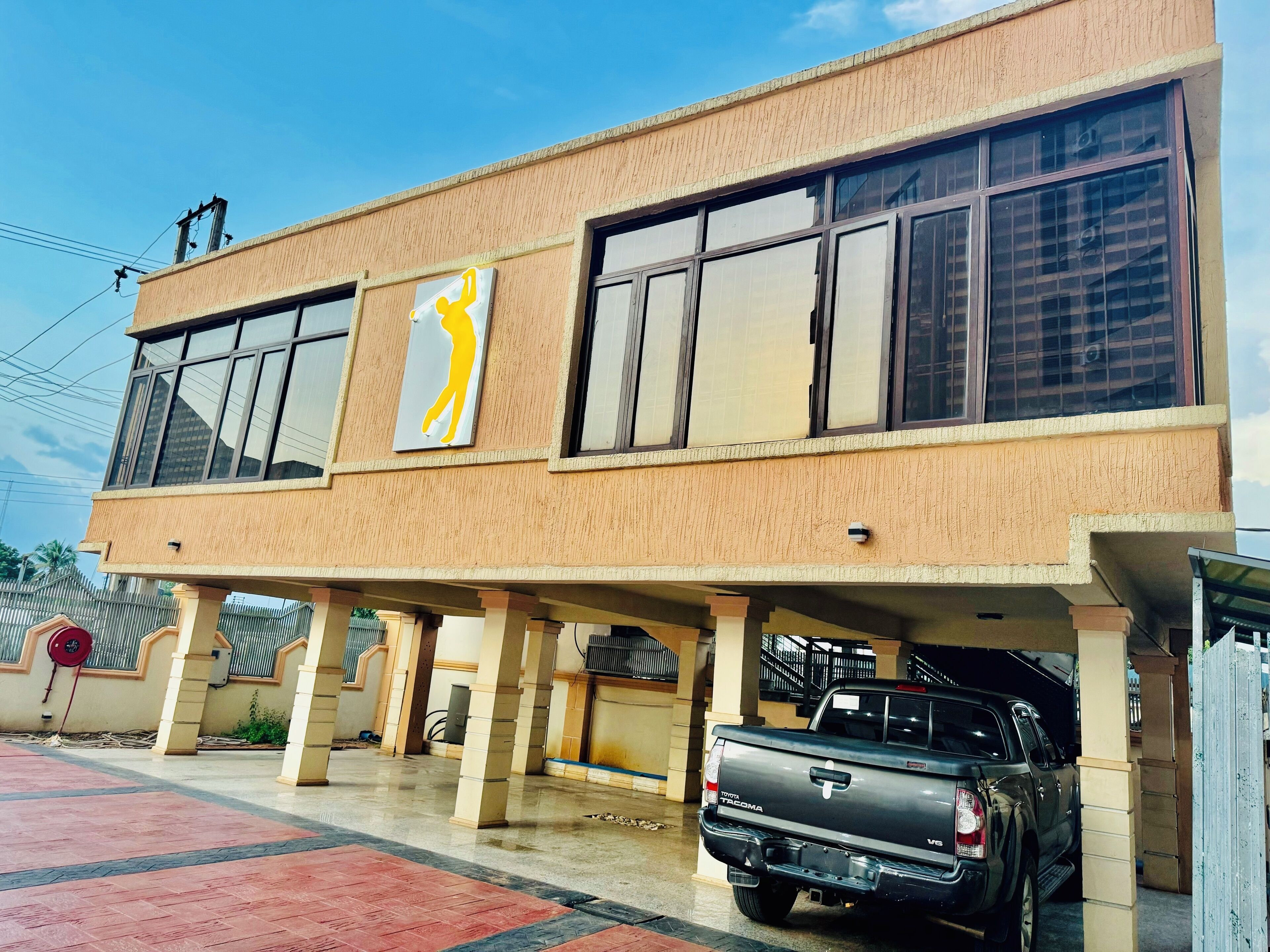 A building with a two-story structure, a visible sign with a yellow figure, and a parked truck.