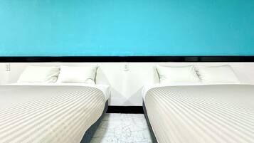 Habitación de hotel con dos camas, piso de mármol y pared color turquesa.