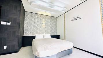 Un dormitorio moderno con cama, armario oscuro, pared con diseño y un aplique de pared.