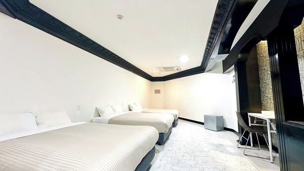 A hotel room with two beds, a small table, and a chair. - ONE STYLE (Naha)