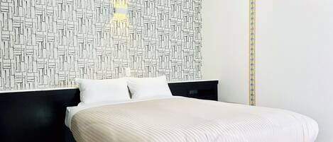 A modern bedroom with a geometric-patterned headboard, a bed with a striped bedspread, and a black nightstand.