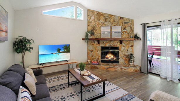 A living room with a stone fireplace, a television, a sofa, and a ceiling fan. - Two Story Private Pool Home Near Bradenton Beach Bayside Paradise (Bradenton)
