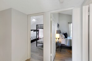 Une pièce comprenant un lit, un bureau et une chaise. Une porte donne accès à une autre pièce.