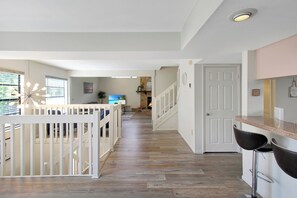 Un intérieur moderne avec un plancher en bois, des murs blancs, un coin cuisine et un escalier.
