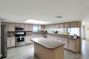 Une cuisine moderne dotée d  ’un îlot central, d’appareils électroménagers en acier inoxydable et de meubles de cuisine en bois clair.