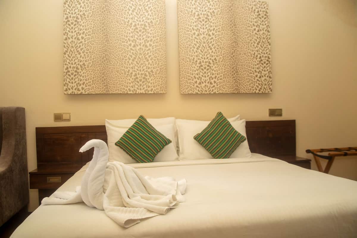 A hotel room with a bed, two leopard print wall decorations, and a swan-shaped towel on the bed.