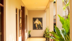 A corridor with a polished floor, wooden doors, and potted plants.
