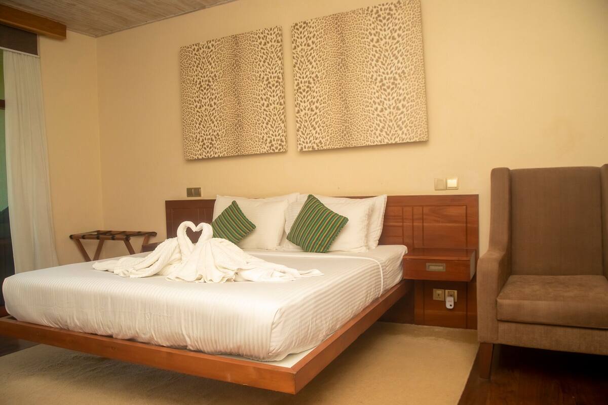 A bedroom with a wooden bed, green and white pillows, and two leopard print wall decorations.