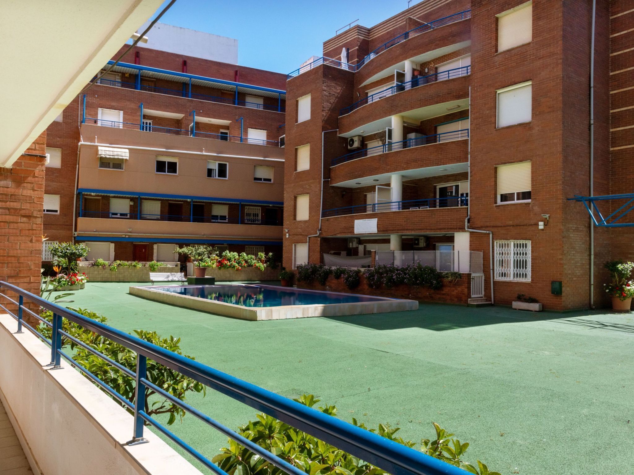 A multi-story residential building with a rooftop pool and green outdoor area.