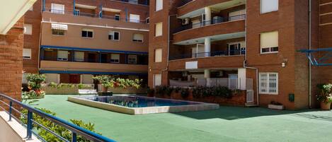 A multi-story residential building with a rooftop pool and green outdoor area.
