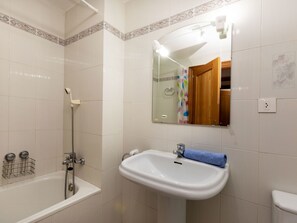 A bathroom with a bathtub, a sink, a mirror, and a shower.