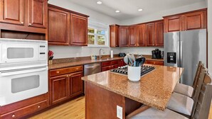 A modern kitchen with wooden cabinets, stainless steel appliances, and a granite countertop. - Theatre~2 Hottubs~MTN Views~Hidden SpeakEasy (Swannanoa)