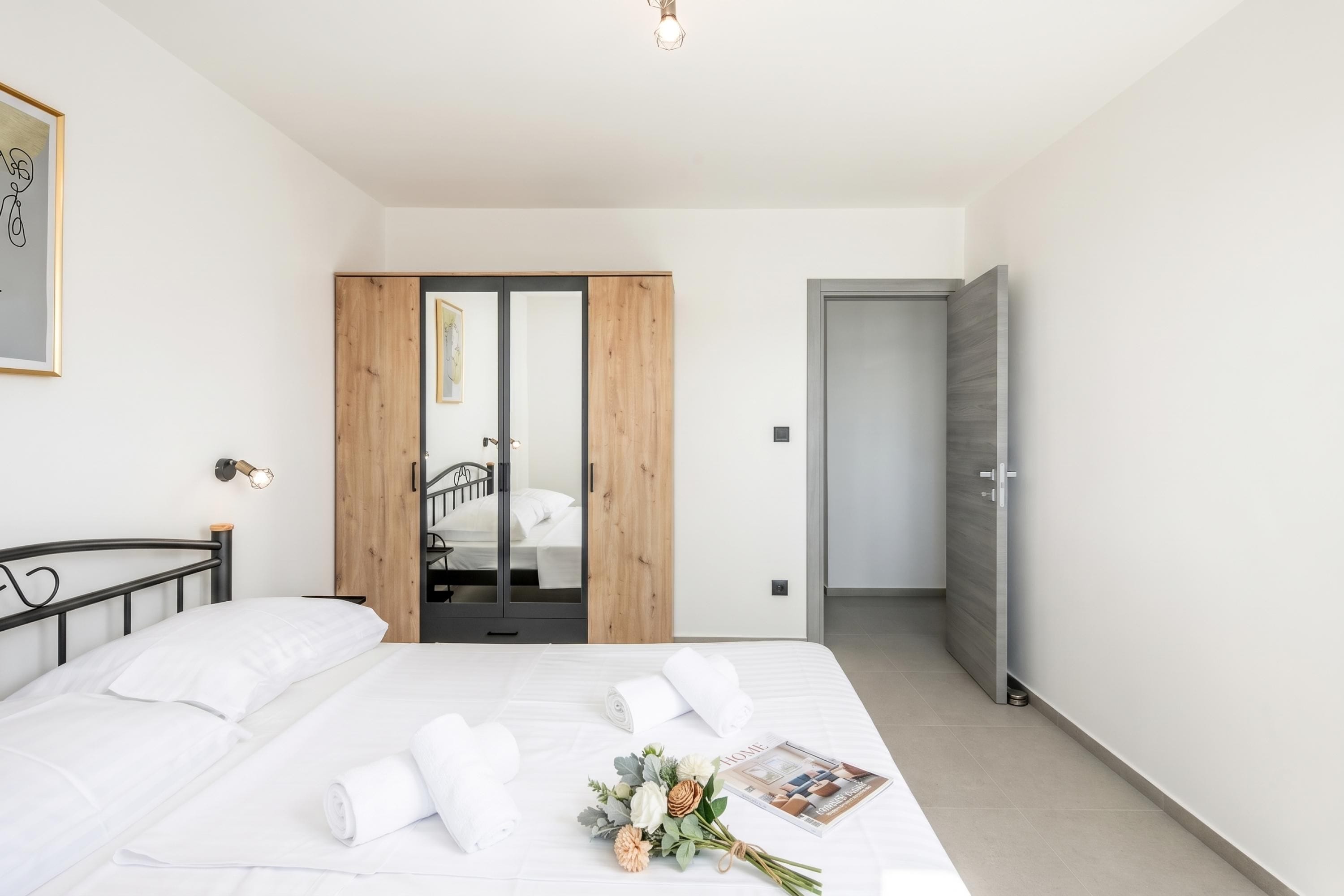 A modern bedroom with a bed, a wardrobe, and a door leading to a staircase.