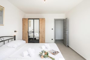 A modern bedroom with a bed, a wardrobe, and a door leading to a staircase.