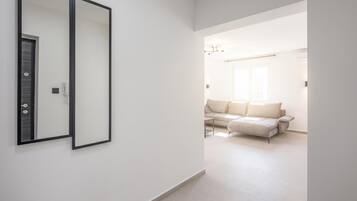 A hallway leading to a living area with a sofa and a mirror on the wall.