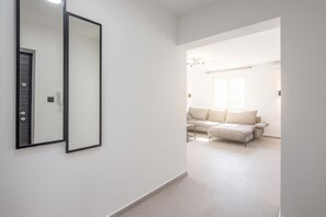 Un pasillo que conduce a una sala de estar con un sofá y un espejo en la pared.