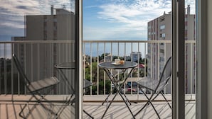 A balcony with two chairs and a small table, overlooking a cityscape with buildings and a clear sky. - City Seaview Apartment Vigo (Rijeka)