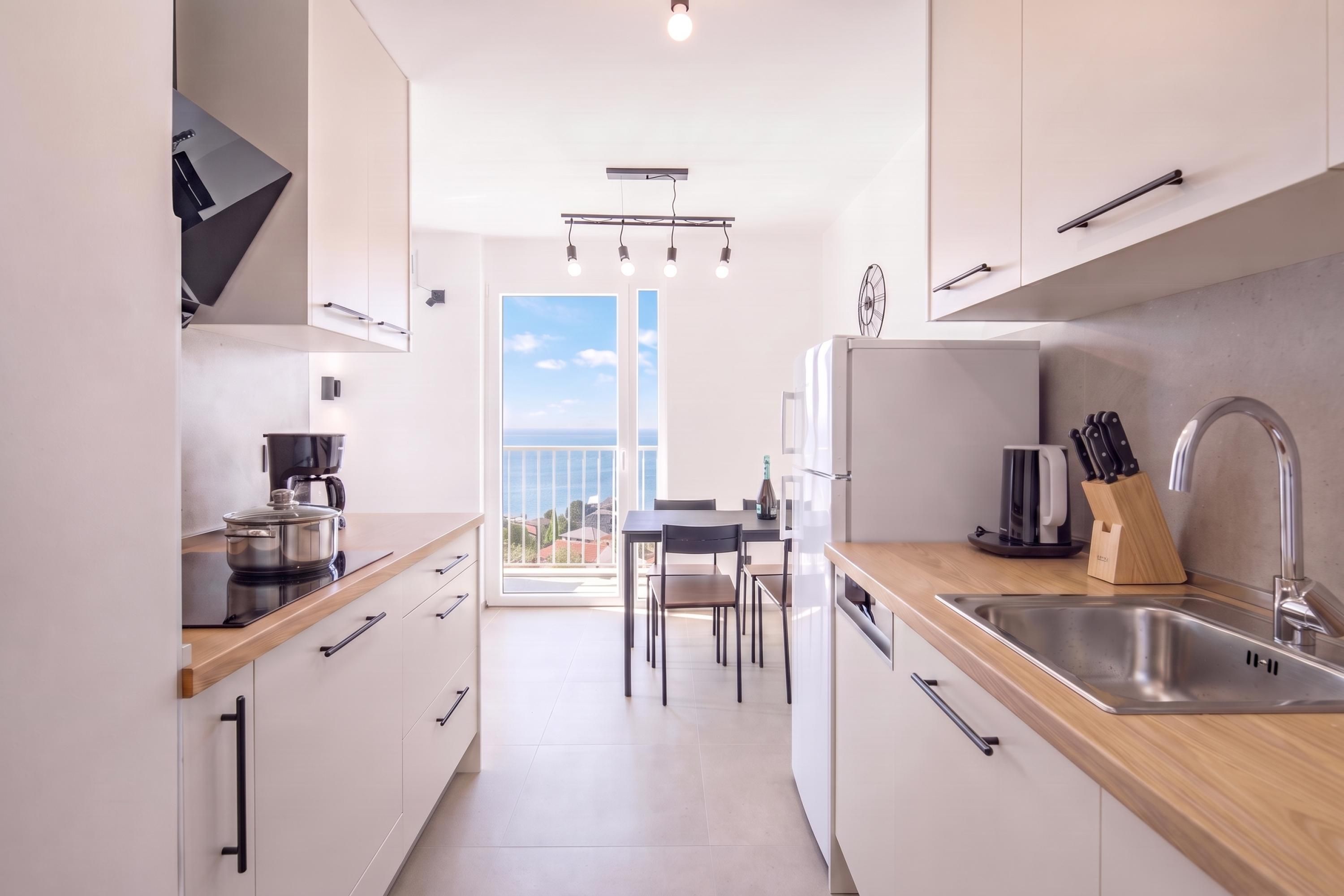 Una cocina moderna con vistas al mar, un comedor y un ventanal grande.