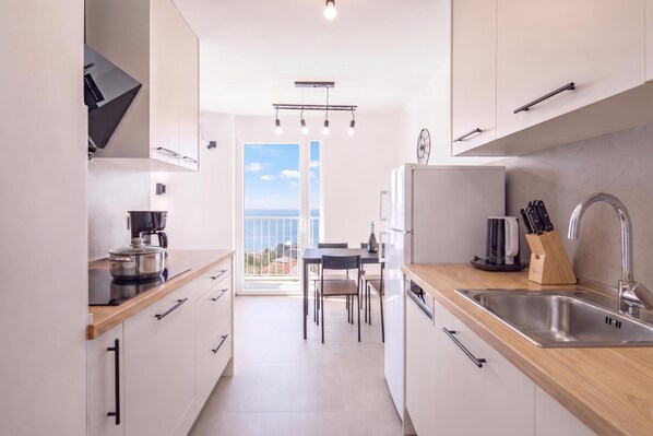 A modern kitchen with a view to the sea, a dining area, and a large window.
