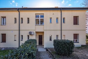 A two-story building with a central entrance, multiple windows, and a visible air conditioning unit. - Quiet City Apartment Dexa (Rijeka)
