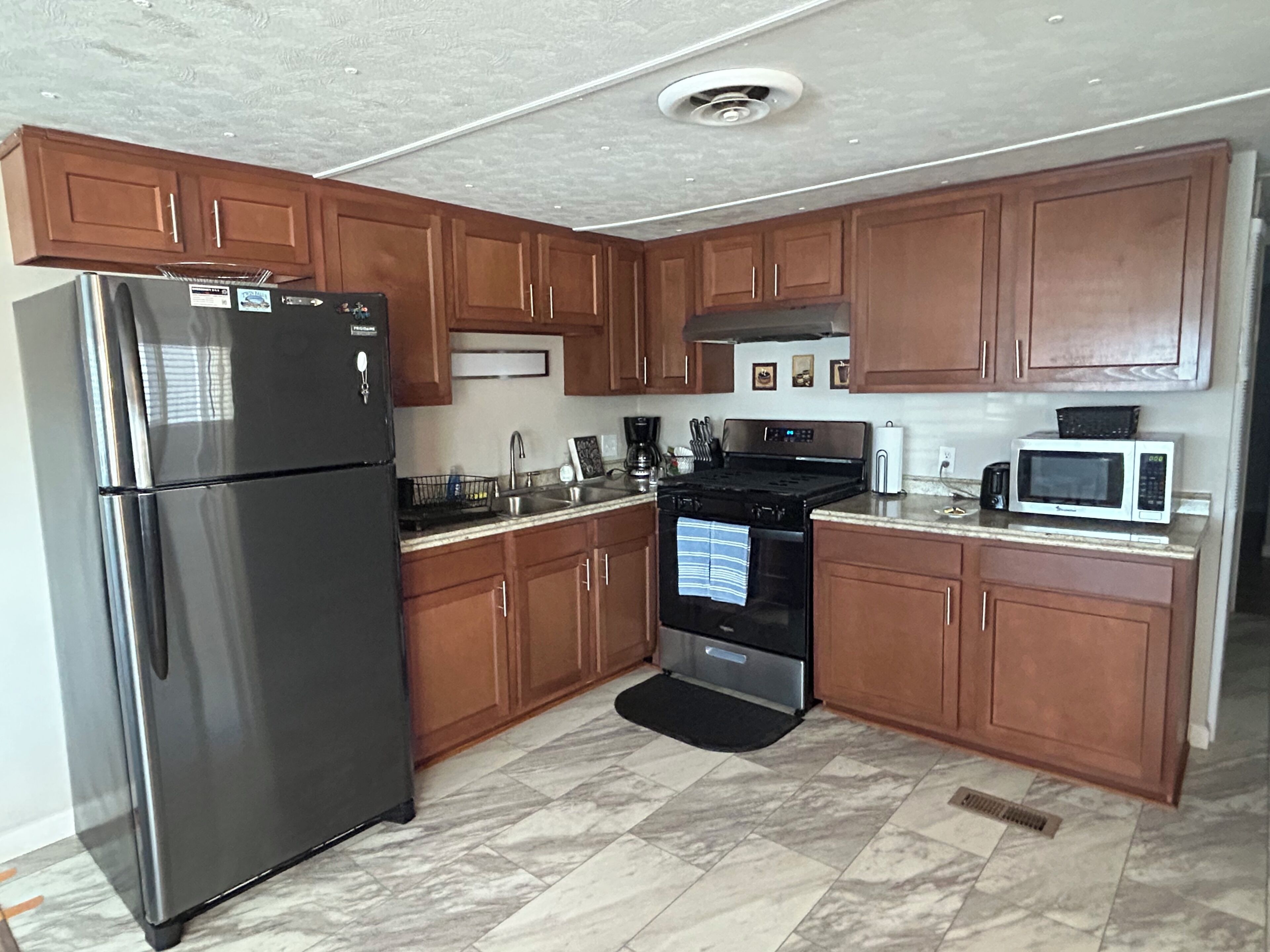 A kitchen with wooden cabinets, a stainless steel refrigerator, a stove, and a microwave.