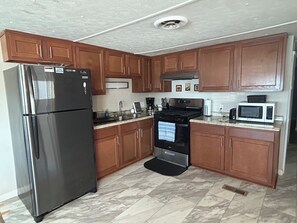 A kitchen with wooden cabinets, a stainless steel refrigerator, a stove, and a microwave.
