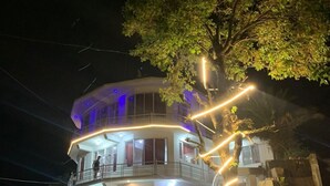 Un edificio de varios pisos con balcones y un coche estacionado adelante.