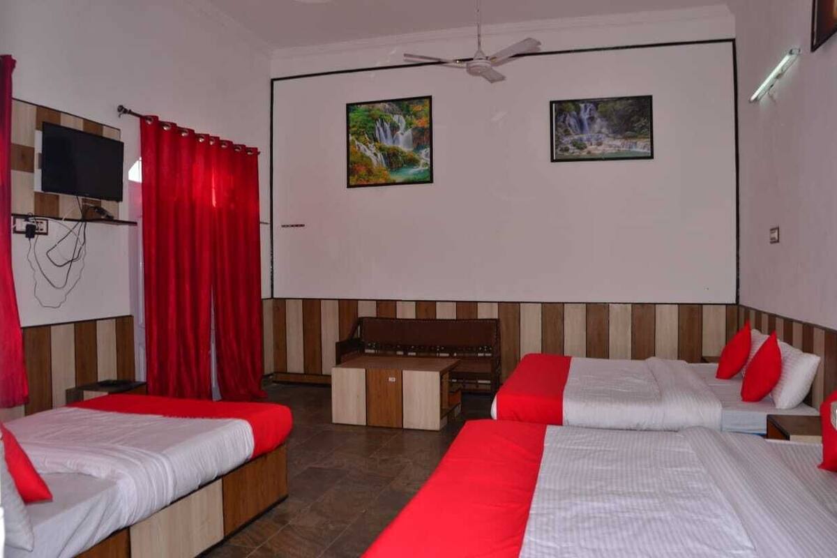 A hotel room with two beds, a TV, and two paintings on the wall.