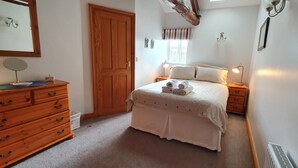 Ein Schlafzimmer mit einem hölzernen Schminktisch, einem Bett mit weißer Bettdecke und zwei Nachttischlampen.