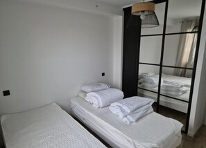 Simple, functional room with a bed, bedside table, and wall-mounted lamp.