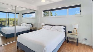 A modern bedroom with a large bed, bedside tables, a mirror, and a window with a view. - Pet-Friendly 3-Bed Coastal Gem Near Long Beach (Long Beach)