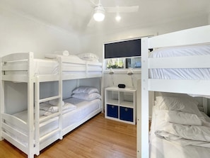 Habitación con literas, escritorio, dos lámparas y ventilador de techo.