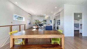 A modern kitchen with a central island, wooden dining table, and chairs.