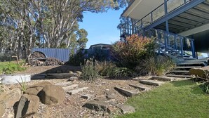 A garden with a stone pathway, large rocks, and a blue fence.