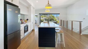 A modern kitchen with a central island, stainless steel appliances, and a view to the outdoors.