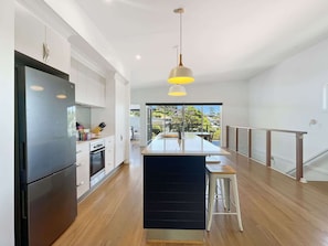 Una cocina moderna con una isla central, electrodomésticos de acero inoxidable y vistas al exterior.