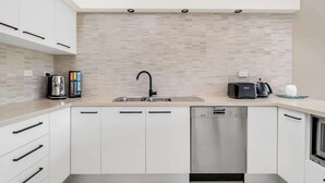 A modern kitchen with a built-in dishwasher, a coffee maker, and a toaster on the counter. - 3-Bed with Beach Views and Entertainment Area (Denhams Beach)