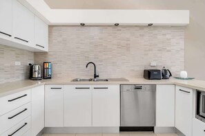 A modern kitchen with a built-in dishwasher, a coffee maker, and a toaster on the counter. - 3-Bed with Beach Views and Entertainment Area (Denhams Beach)