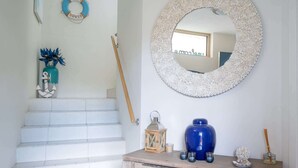 A staircase with white tiles, a wooden door, a blue vase, and a mirror with a floral frame. - 3-Bed with Beach Views and Entertainment Area (Denhams Beach)