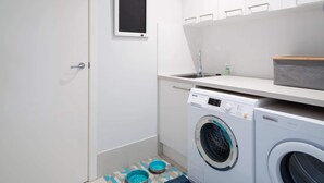 A compact laundry room with a washing machine, a dryer, a sink, and a small window. - 3-Bed with Beach Views and Entertainment Area (Denhams Beach)