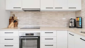 A modern kitchen with white cabinetry, a Bosch oven, and a coffee maker. - 3-Bed with Beach Views and Entertainment Area (Denhams Beach)