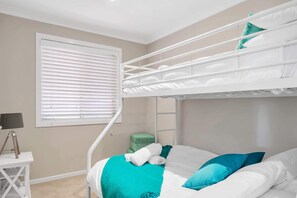 A bunk bed room with a window, a desk, and a lamp. - 3-Bed with Beach Views and Entertainment Area (Denhams Beach)