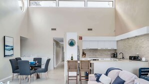 A modern living room with a sofa, dining area, and kitchen. - 3-Bed with Beach Views and Entertainment Area (Denhams Beach)