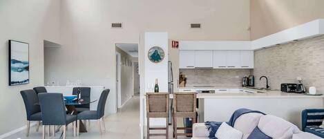 A modern living room with a sofa, dining area, and kitchen.